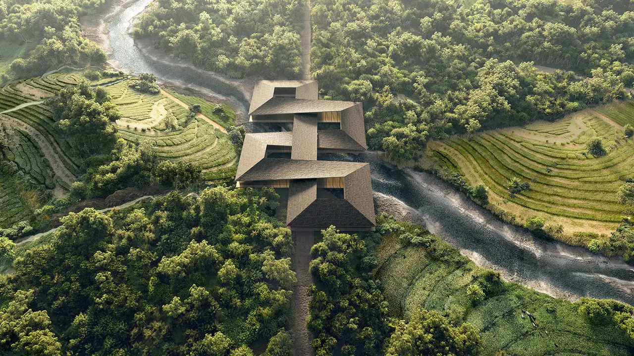 Aerial view of a riverside building surrounded by forests and terraced fields in Gelephu